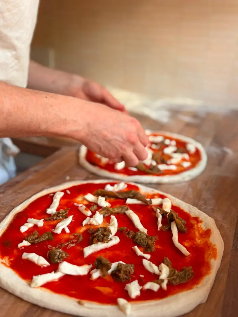 Two pizzas being made